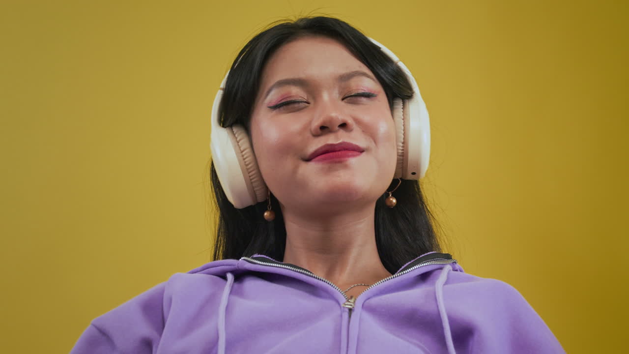 Asian Woman Choosing Song on Smartphone to Listen via Headphones