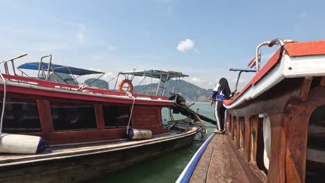 person stepping between docked boats on a clear day