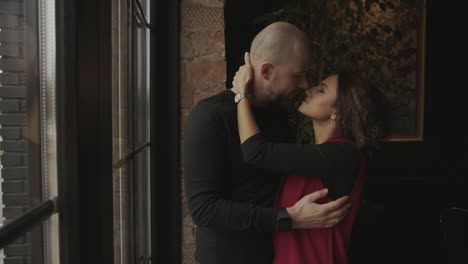 couple kissing by a window