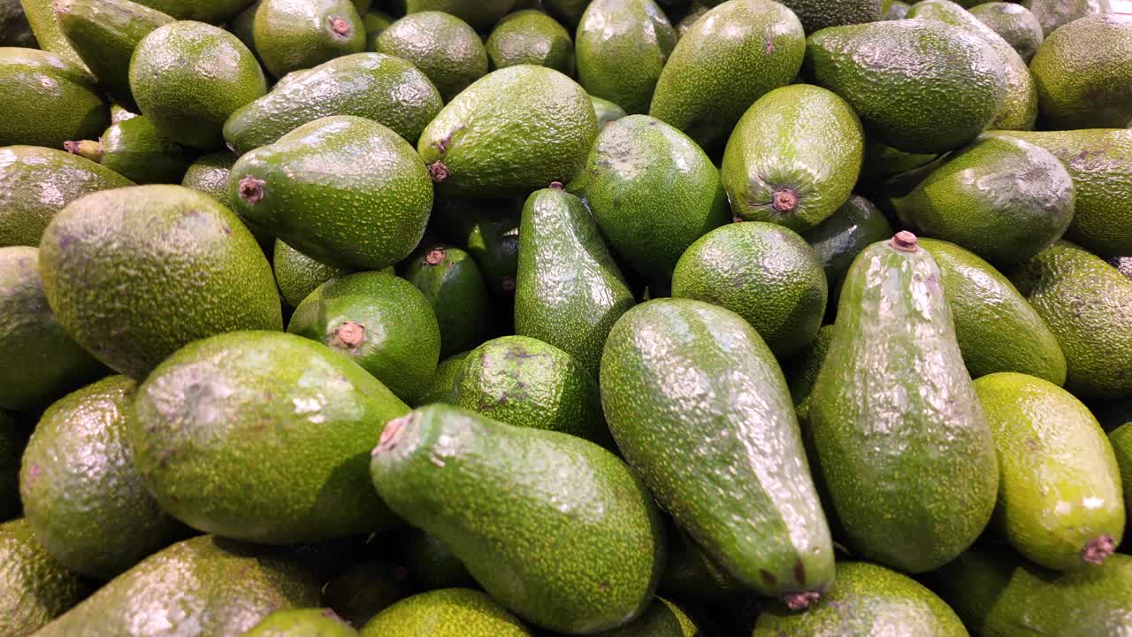 A pile of fresh green avocados