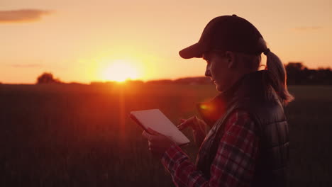 Eine-Bäuerin-Arbeitet-Bei-Sonnenuntergang-Auf-Dem-Feld-Und-Genießt-Eine-Tablet-Technologie-Im-Agrobusiness-4k