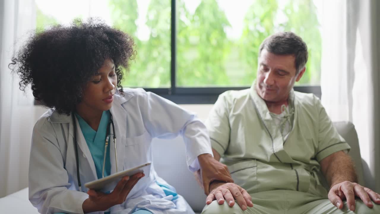 African American female medical doctor using digital tablet explain the symptoms to the patient after treatment or talking with old man patient in the hospital.