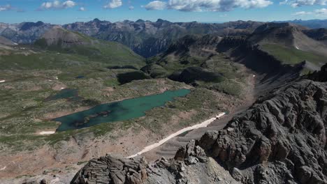 Aerial-View-of-San-Juan-National-Forest-and-Mountain-Range-With-Glacial-Lake-Under-Rocky-Hills,-Colorado-USA,-Drone-Shot