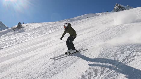 professioneller männlicher abfahrtsskifahrer, der schnelle und sportliche slalom-ski-schwünge auf einer perfekt präparierten skipiste in einem resort in den bergen fährt