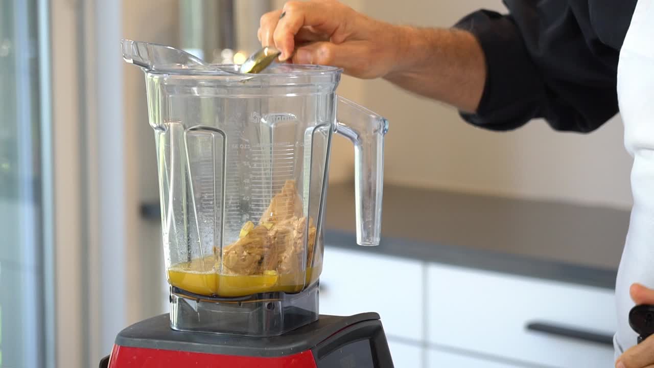 agregando agave en una licuadora de mantequilla de almendra y jugo de naranja para hacer salsa para fideos de calabacín zoodles