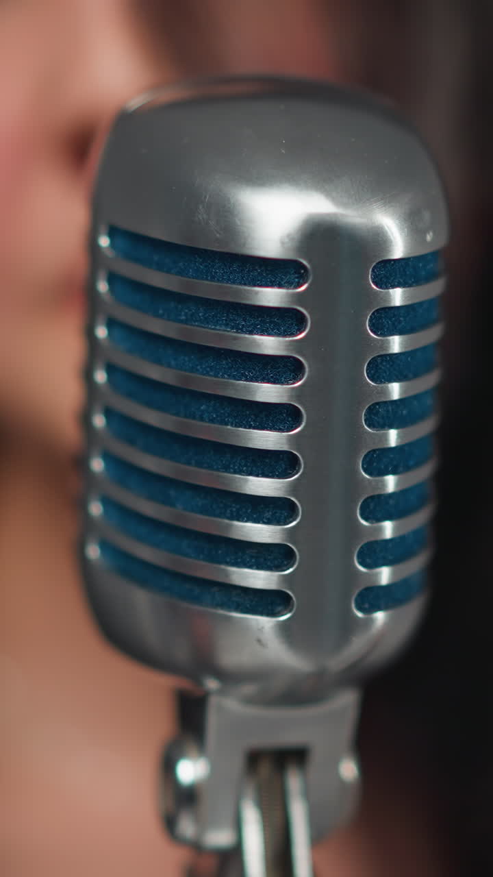 cantante femenina emotiva en traje negro actuando enérgicamente en un micrófono con un tecladista masculino en el fondo en un conjunto minimalista
