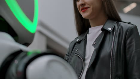 una chica sonriente con una camiseta blanca está en contacto con un humanoide. cyborg ayuda a la chica a responder preguntas. asistente robótico útil en la oficina y en el centro comercial