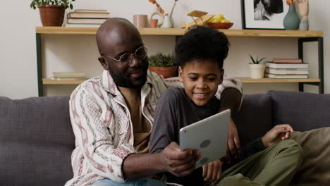 father and son using tablet in the living room