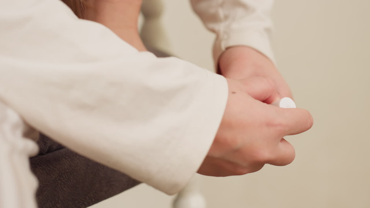 Hand view of female painting toes with black polish, soft sleeve visible, close grooming on chair, gentle self care pedicure at home, calm focus, relaxed indoor beauty routine in warm setting