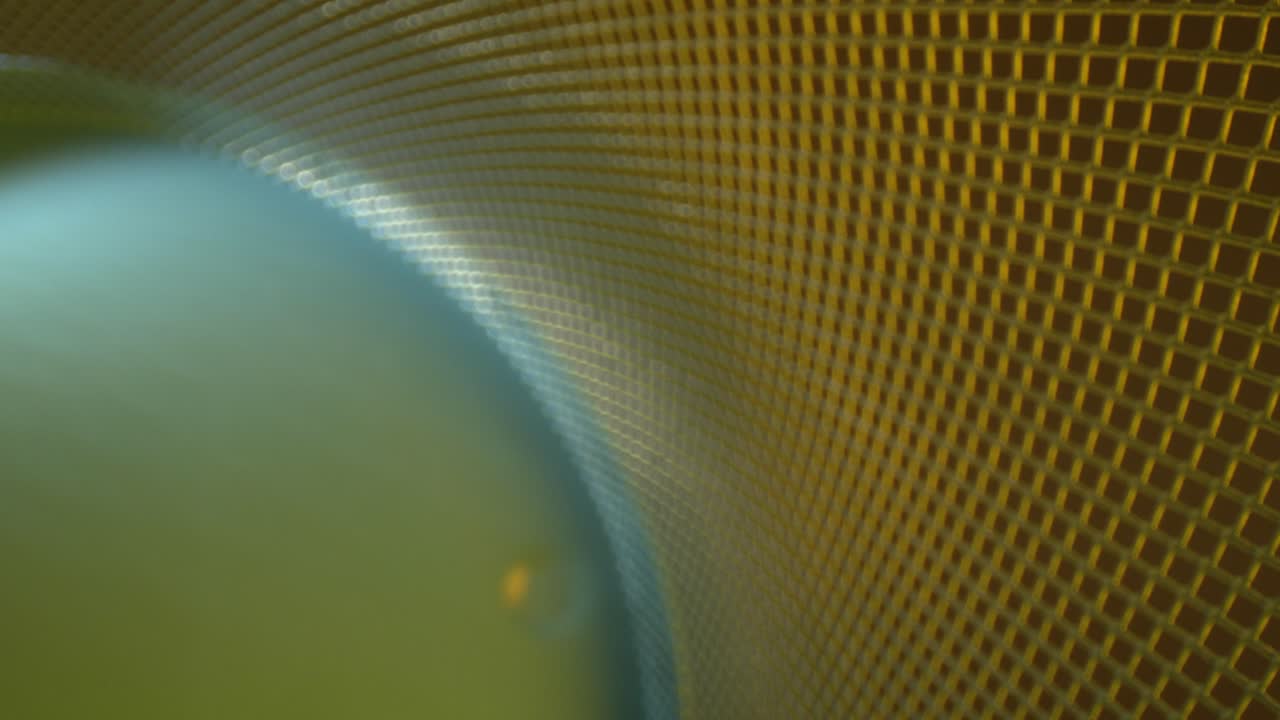 Pulling away from a DEFOCUSED metal lattice grid where the base is lit bright light blue and the grid is dark yellow gold