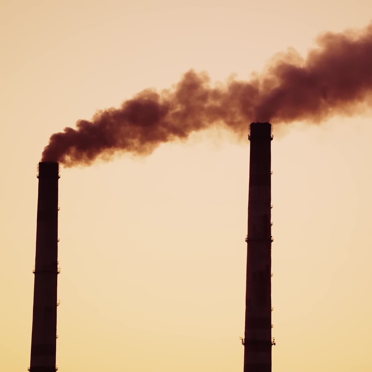 Industrial pipes with dark smoke at sunset. Dirty chemical smoke coming out from two pipes in the evening. Air pollution. Close-up.