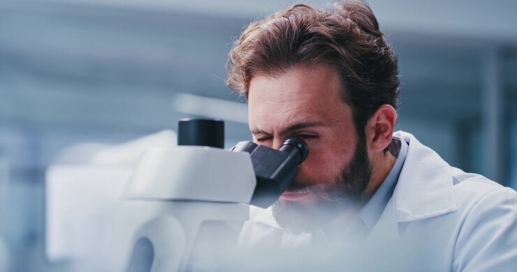 Scienziato che esamina campioni al microscopio in laboratorio