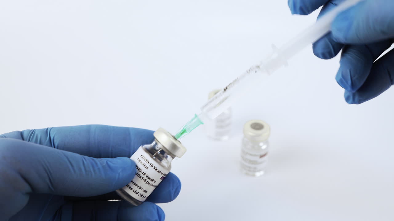 Hands with syringe taking anti covid vaccine from vial. Static, shallow focus