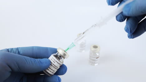 hands with syringe taking anti covid vaccine from vial. static, shallow focus