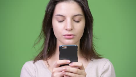 joven hermosa usando el teléfono contra un fondo verde