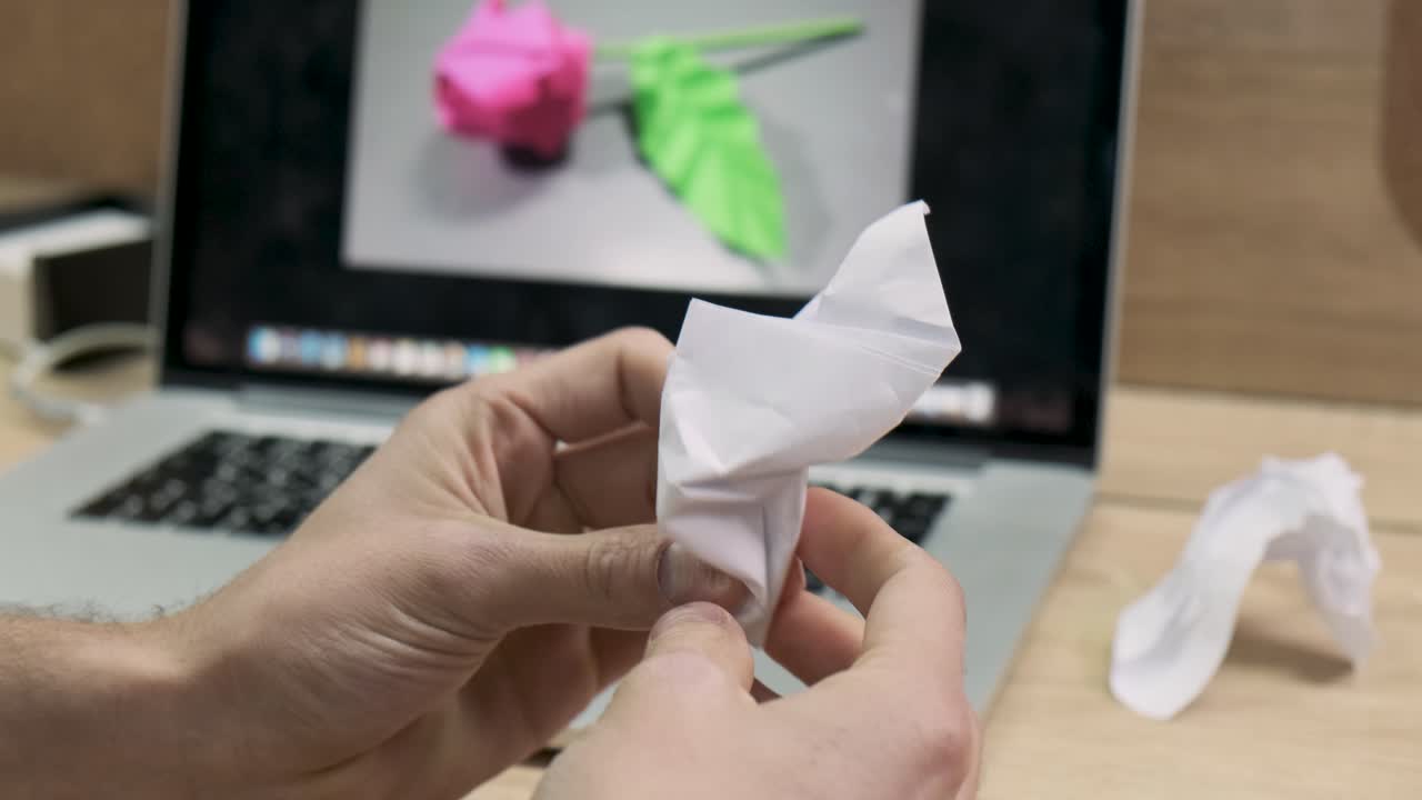 persona haciendo origami en una computadora portátil