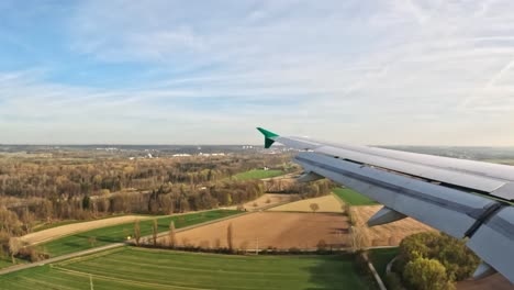 an airplane wing over scenic fields during descent into munich, germany, aerial view