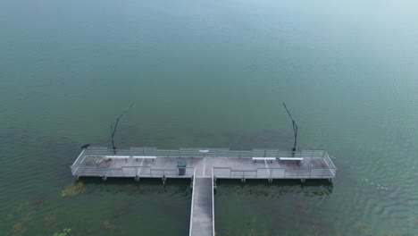 flyover of fishing dock and aerial reveal of starke lake and cloudy sky in ocoee, central florida