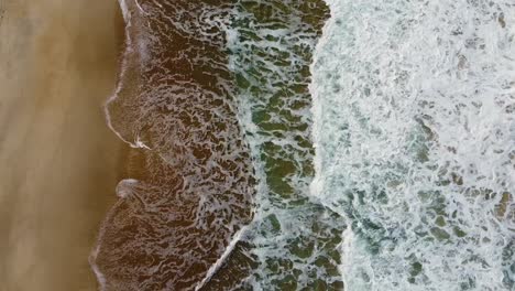 Schaumige-Wellen-Krachen-In-Den-Strand,-Die-Luft-Kippt-Nach-Unten