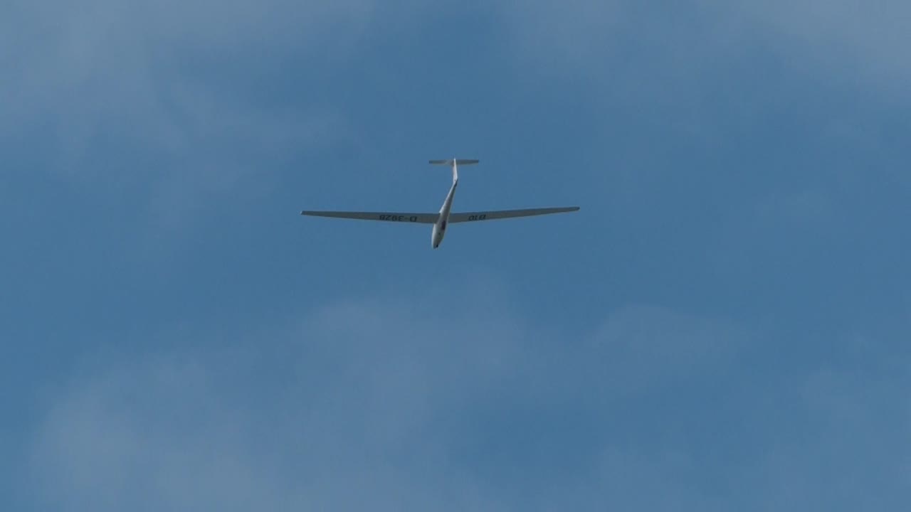 white glider is pulled in the sky by winch and flies through the sky
