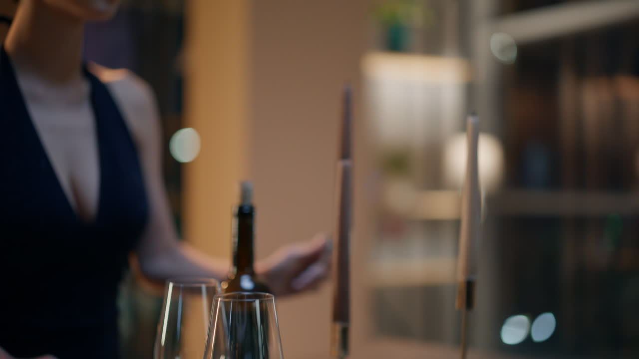 Primo piano di una donna che sistema il cibo, preparando la serata per l'anniversario. La signora accende le candele.