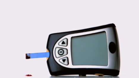 drop of blood falling from test strip of blood glucose monitor