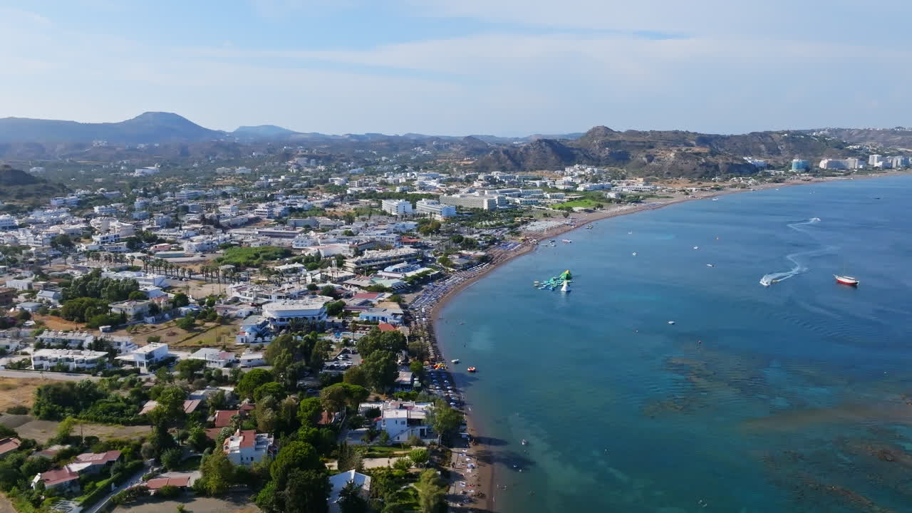 Aerial tracking in front of the beach and town, sunny day in Faliraki, Rhodes