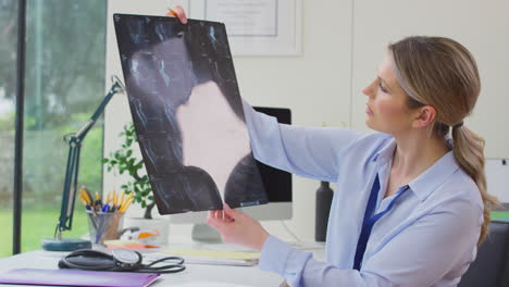 mujer médico o médico de cabecera sentada en el escritorio en la oficina mirando la tomografía computarizada o resonancia magnética