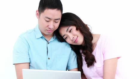 smiling asian couple using laptop together