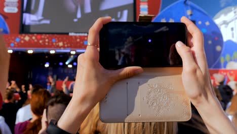 woman recording video of live music concert with smartphone