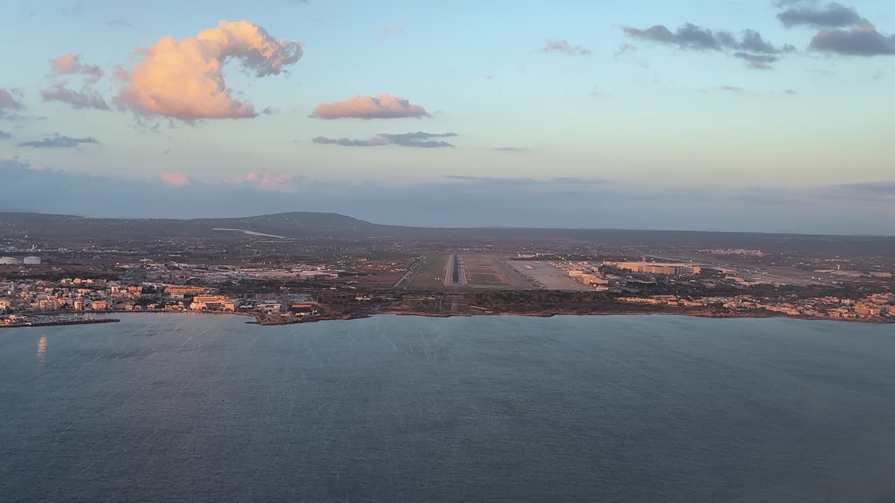 An immersive pilot’s perspective in the final approach to Palma de Mallorca airport at sunset, in a windy afternoon, with some orange color clouds, and the runway ahead