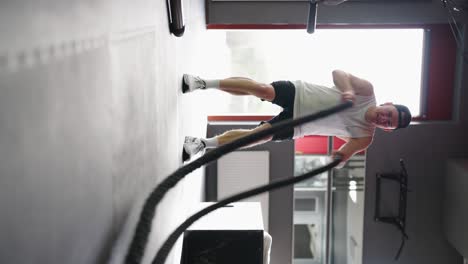 vertical video of athlete do high intensity battle rope workout at gym