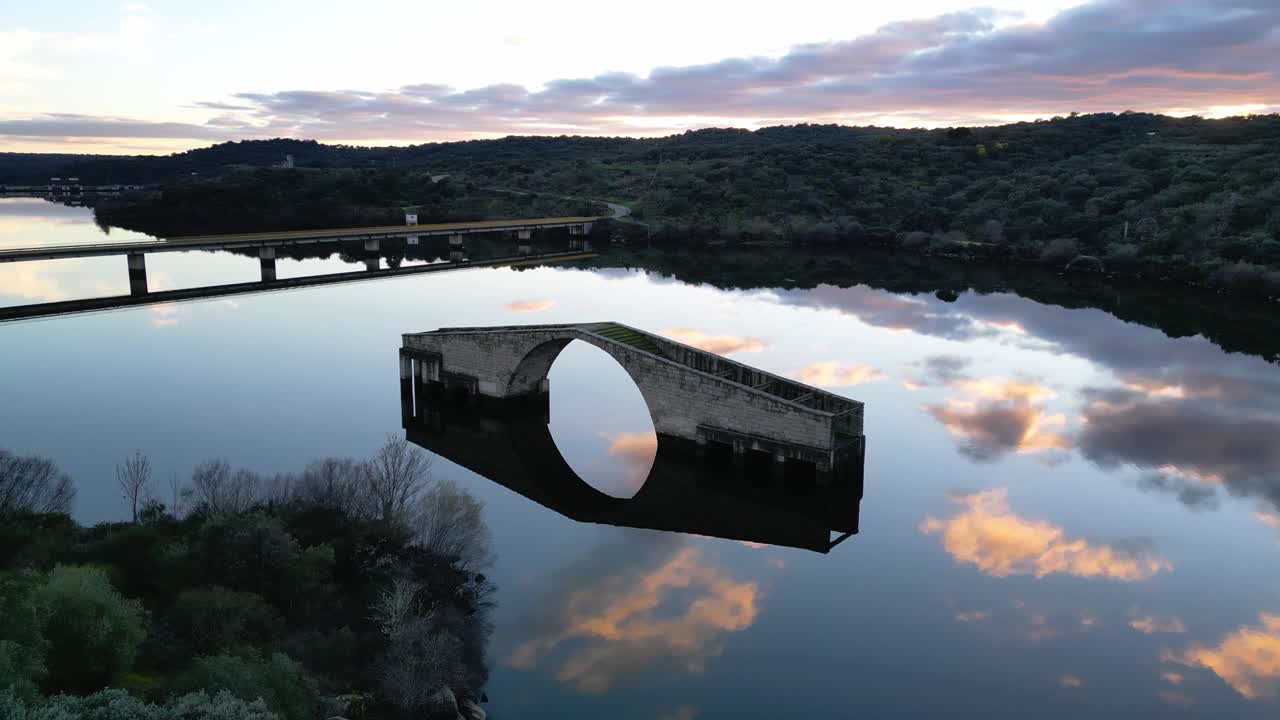 Aerial drone view of the Roman Bridge of El Ponton in Guijo de Granadilla, Extremadura. Historic stone structure surrounded by rural landscape