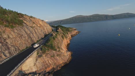 vehicle driving on coastal mountain road in norway, fpv drone follow view