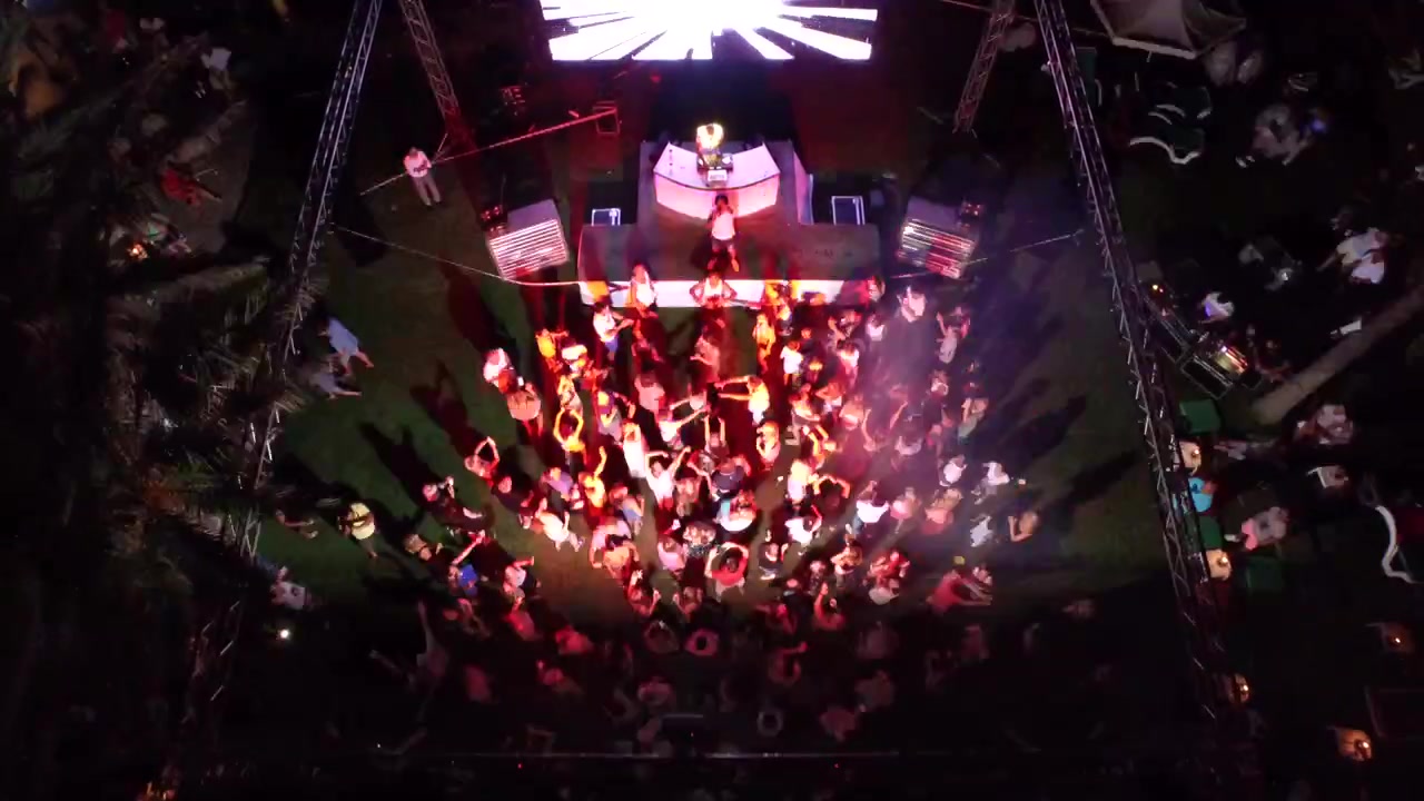 Aerial View of Nighttime Beach Party with DJ and Dancing Crowd