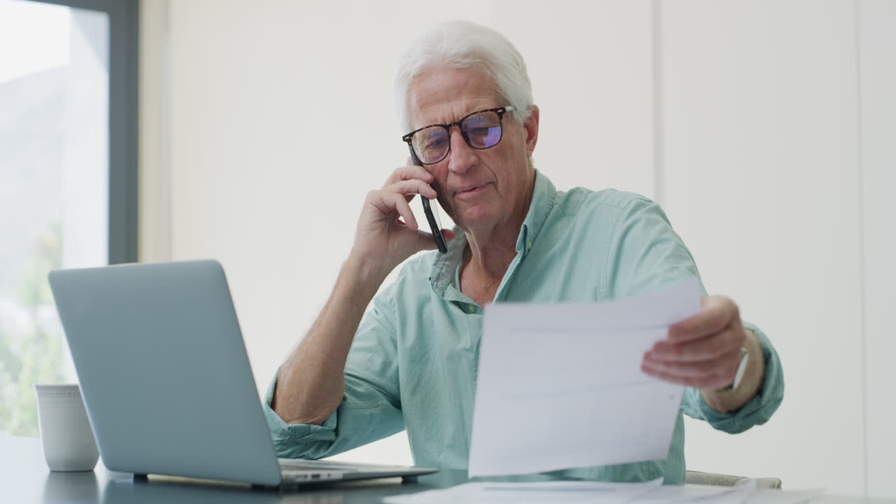 un anciano en el teléfono comprobando documentos.