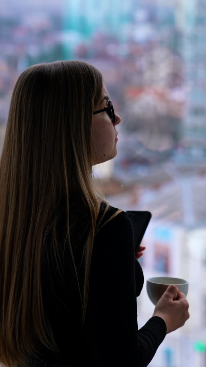 Beautiful woman wearing eyeglasses using cellphone and drinking coffee Vertical video