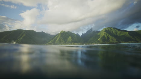 tahitian island mountains reflect in ocean water, view from surface