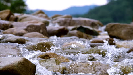 clear stream running through stone boulders abundant river flowing in slow motion