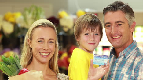 smiling family with paper bag showing credit card