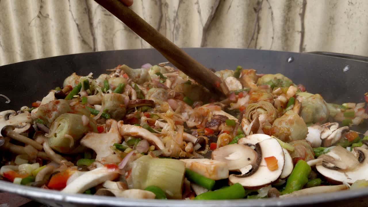 Wooden spoon moving food across hot pan on a stove