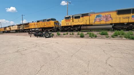 POV - Driving toward a line of Union Pacific diesel locomotive engines; turning to drive along the train tracks on the edge of small Midwestern town;hometown
