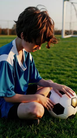 a young boy sitting on a soccer field