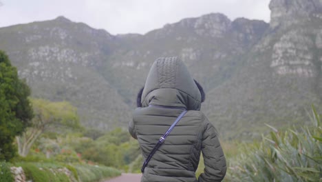 lady walking with a mountain in the background on a windy cloudy day