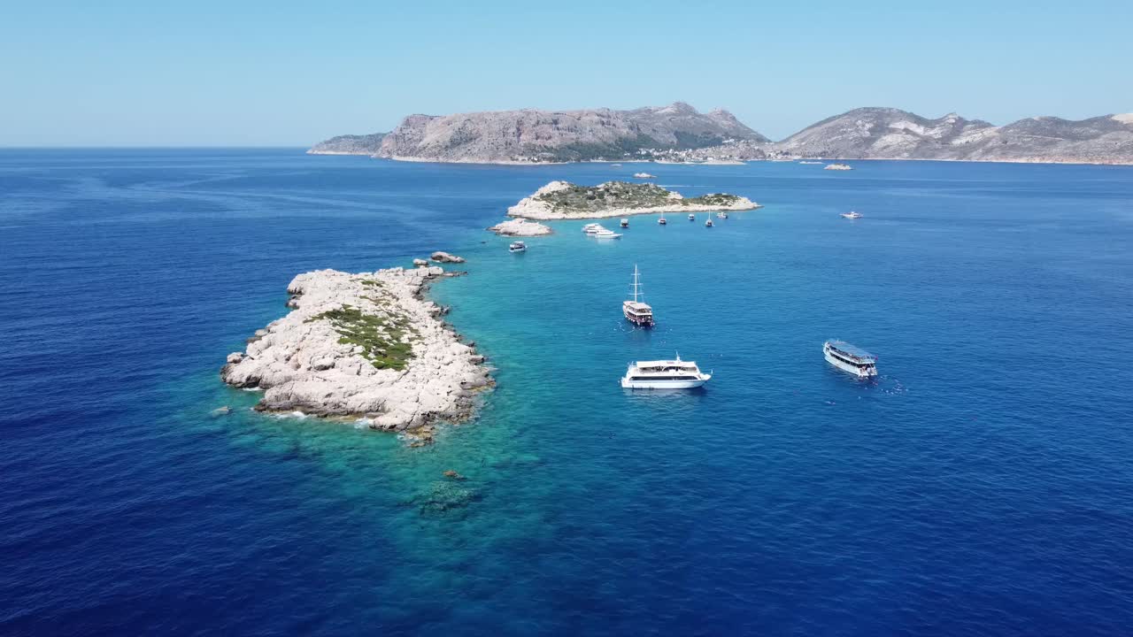 Aerial drone view showing island dotted coastline with leisure boats near Gocek Bay in Mugla, capturing clear turquoise water, rocky islets, calm sea surface, and bright summer atmosphere