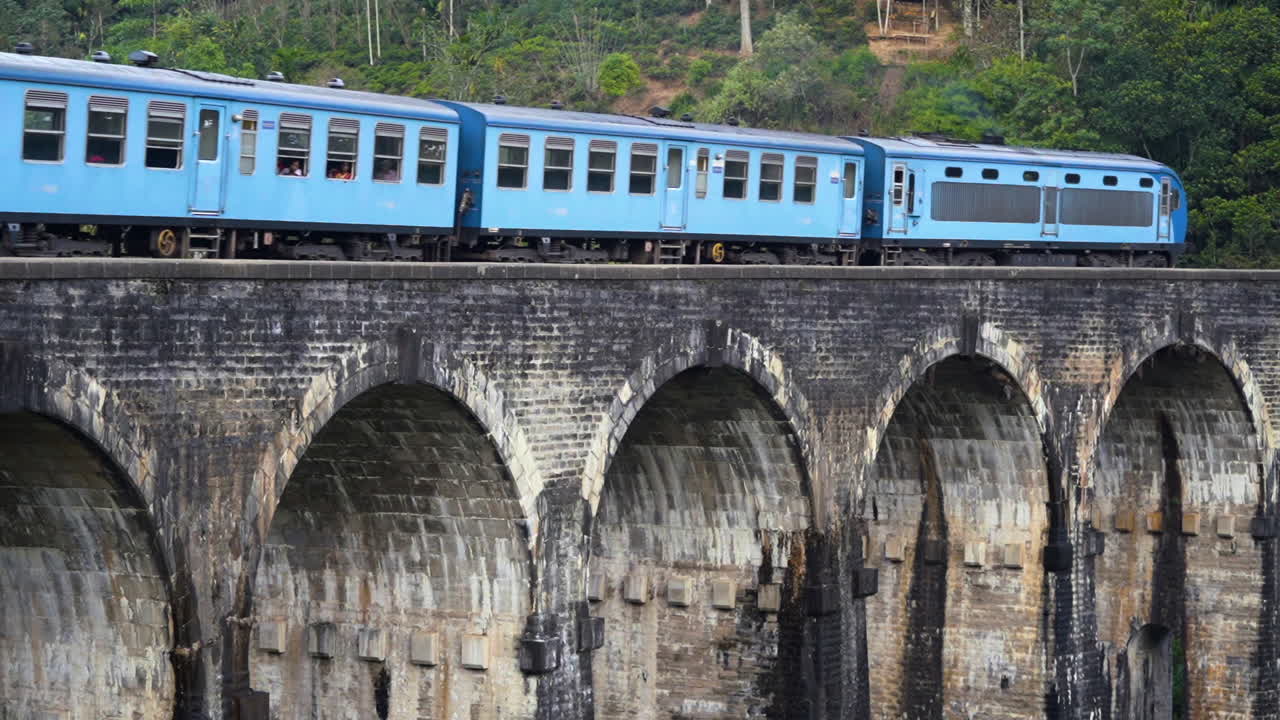 un tren de pasajeros envejecido pasa sobre el puente de nueve arcos cerca de ella en sri lanka