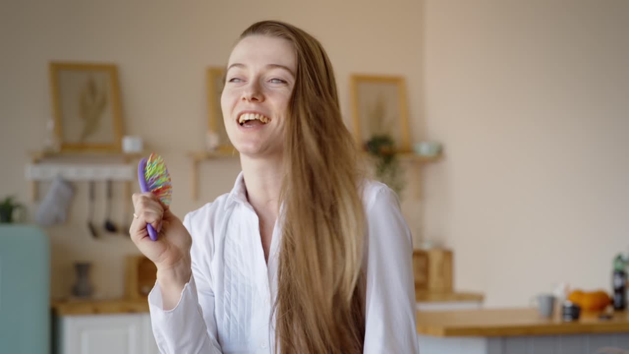 Woman singing with a hairbrush in the kitchen