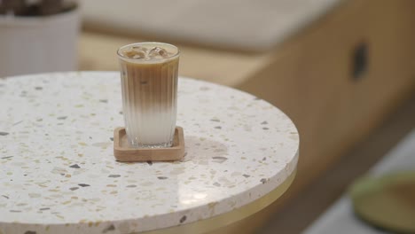 iced latte on a terrazzo table with a hand
