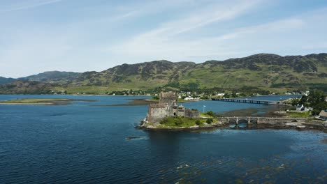 Amplia-Vista-Aérea-En-órbita-Del-Castillo-De-Eilean-Donan-En-Las-Tierras-Altas-De-Escocia