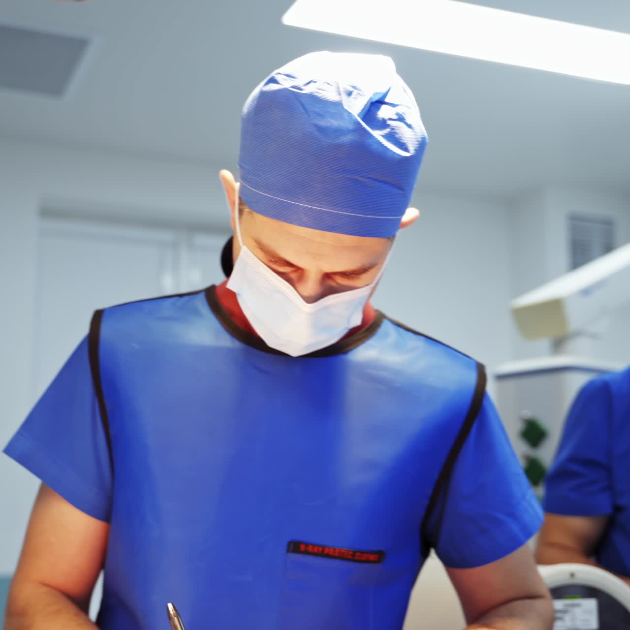 Medical specialist in clinic looking down. Doctor in medical uniform and mask in the operating room. Healthcare concept.